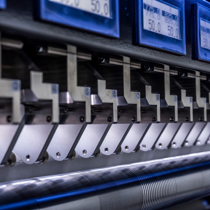 Cutting-blade units lined up on a slitter and a digital panel showing dimensions
